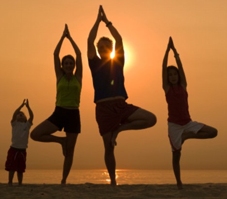 41 year old woman, her 3 year old son, 11 year old daughter and husband practice yoga, the tree pose or Vrksasana. on the beach in Santa Monica, Ca. at sunset, children are mxed race, Japanese/white